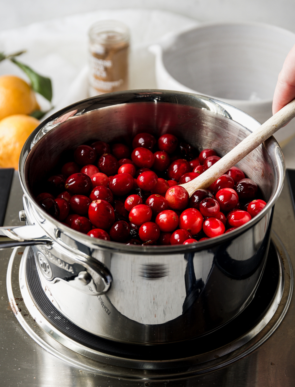 Stirring cranberries with a wooden spoon.