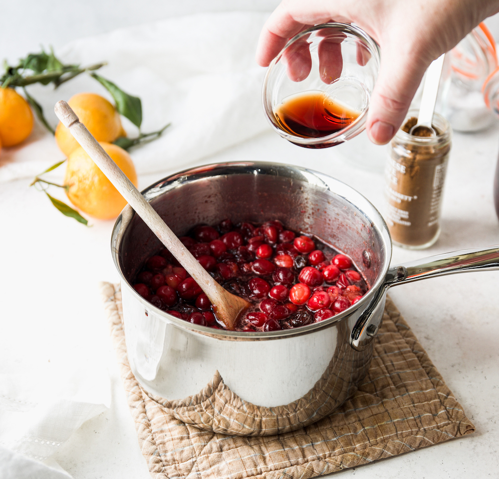 Pouring red wine vinegar into cranberry sauce.