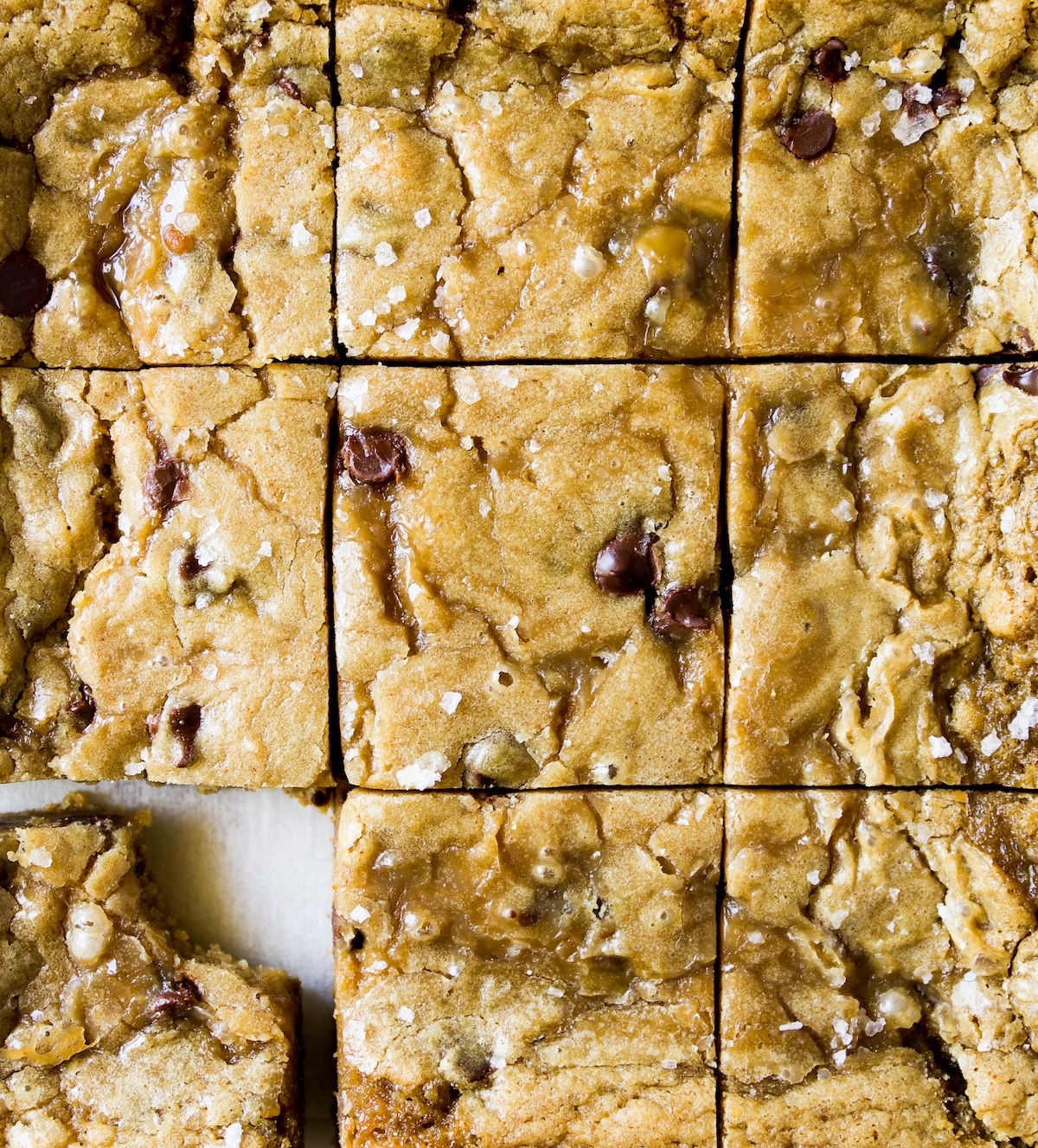 Blondies that have just been cut; one with a bite out of it.