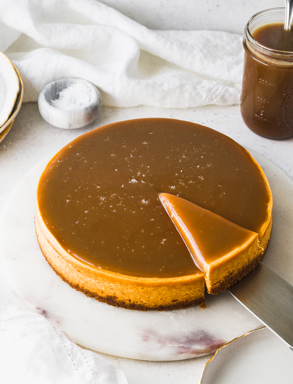 A whole pumpkin cheesecake covered in caramel with a white background.
