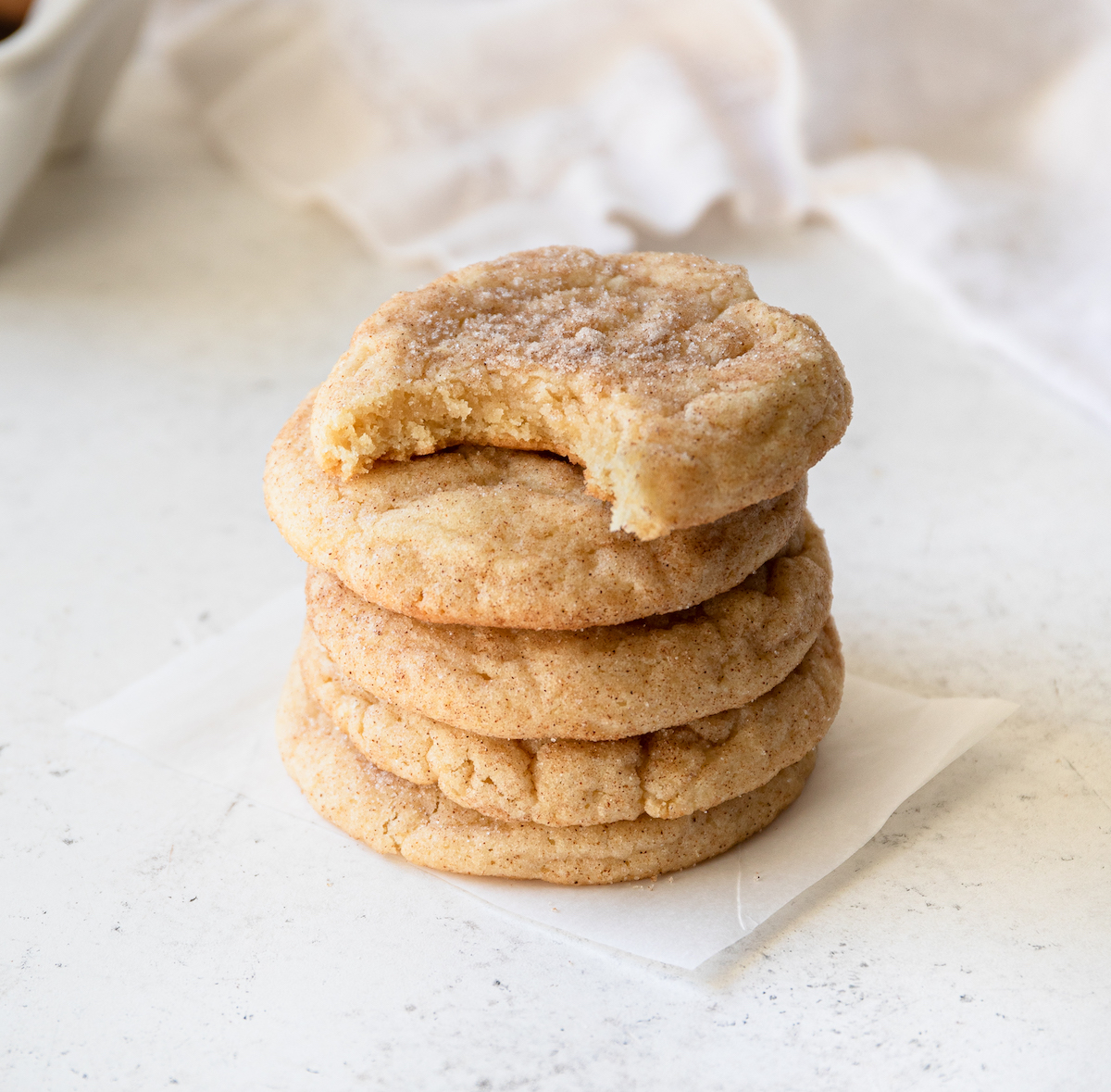 A stack of snickerdoodle cookies on a white surface.