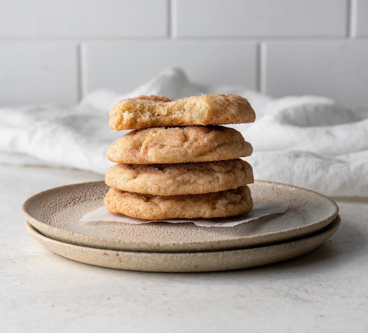 A stack of snickerdoodles on a plate with a bite out of one of them.