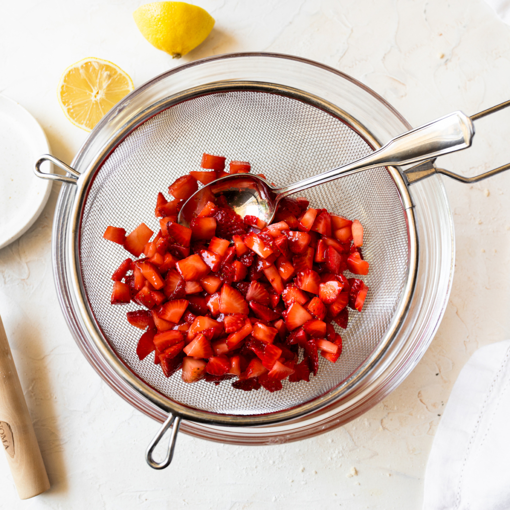 Chopped strawberries in a sieve.