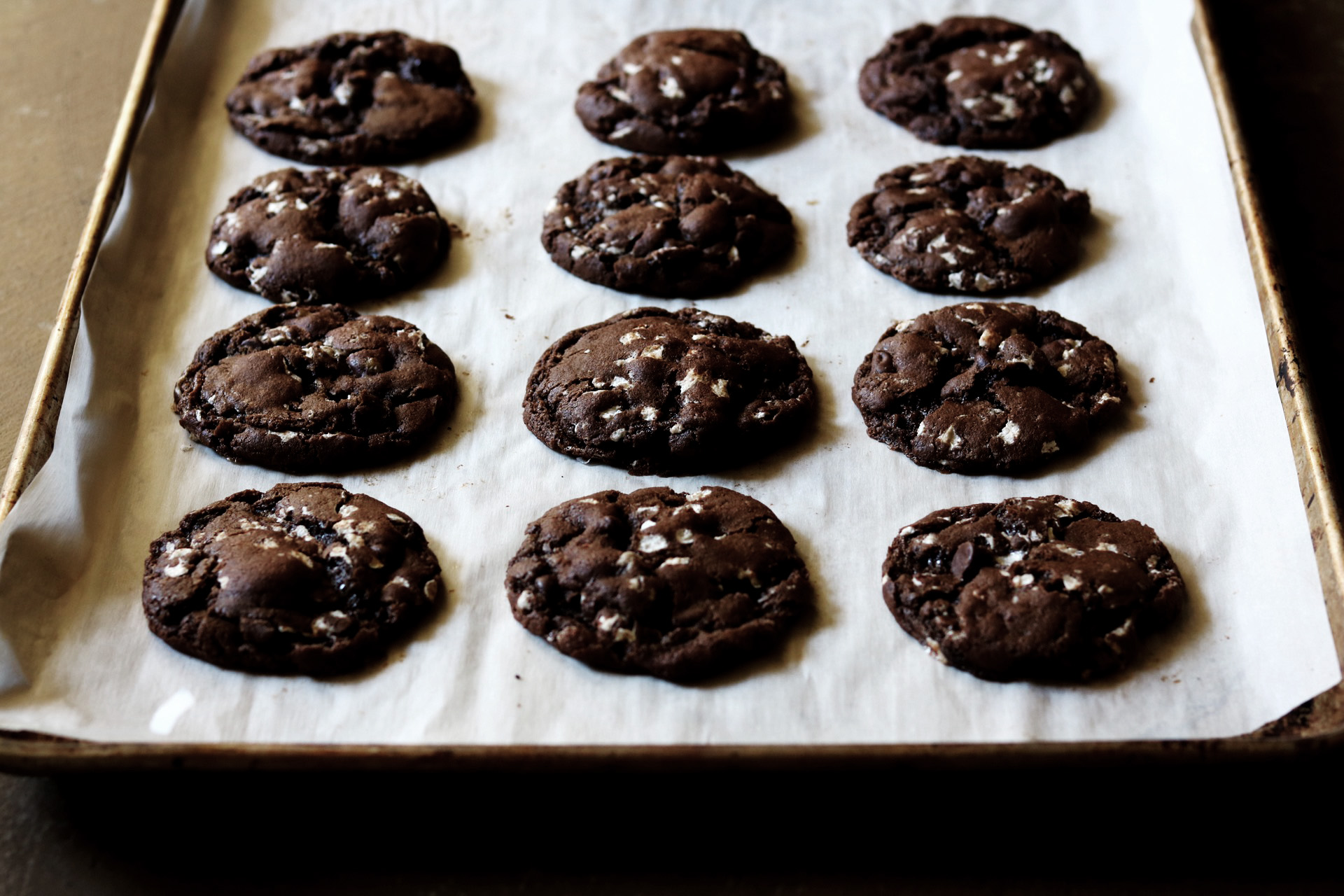 Chocolate marshmallow cookies on a baking sheet lined with parchment paper.