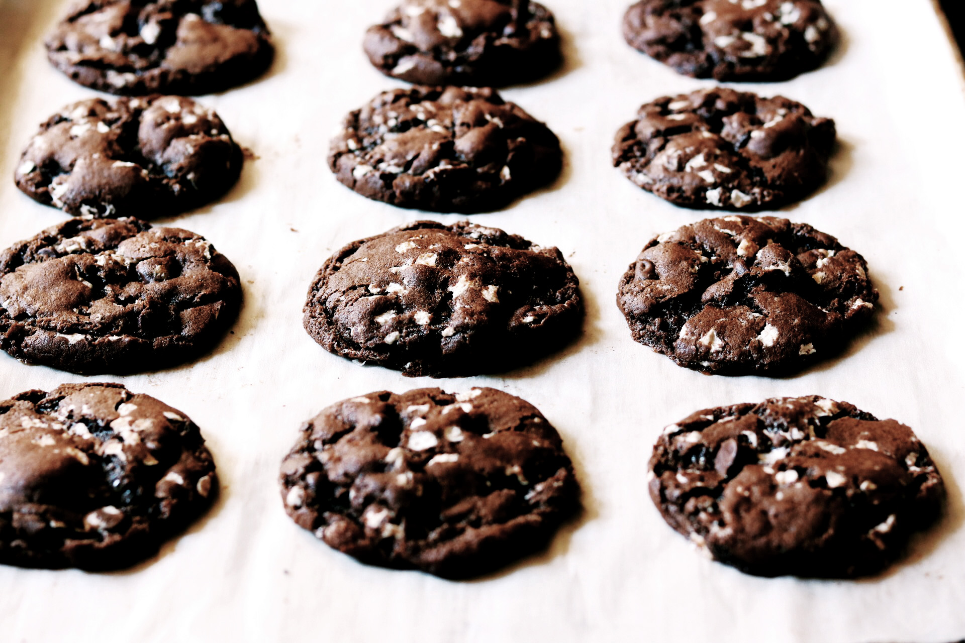 Chocolate cookies with marshmallow on a baking sheet.