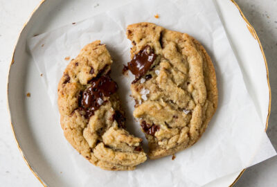A close up of a chocolate chip cookie on a white surface.