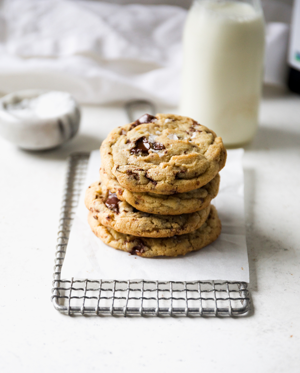 A stack of cookies with a glass jar of milk in the background.