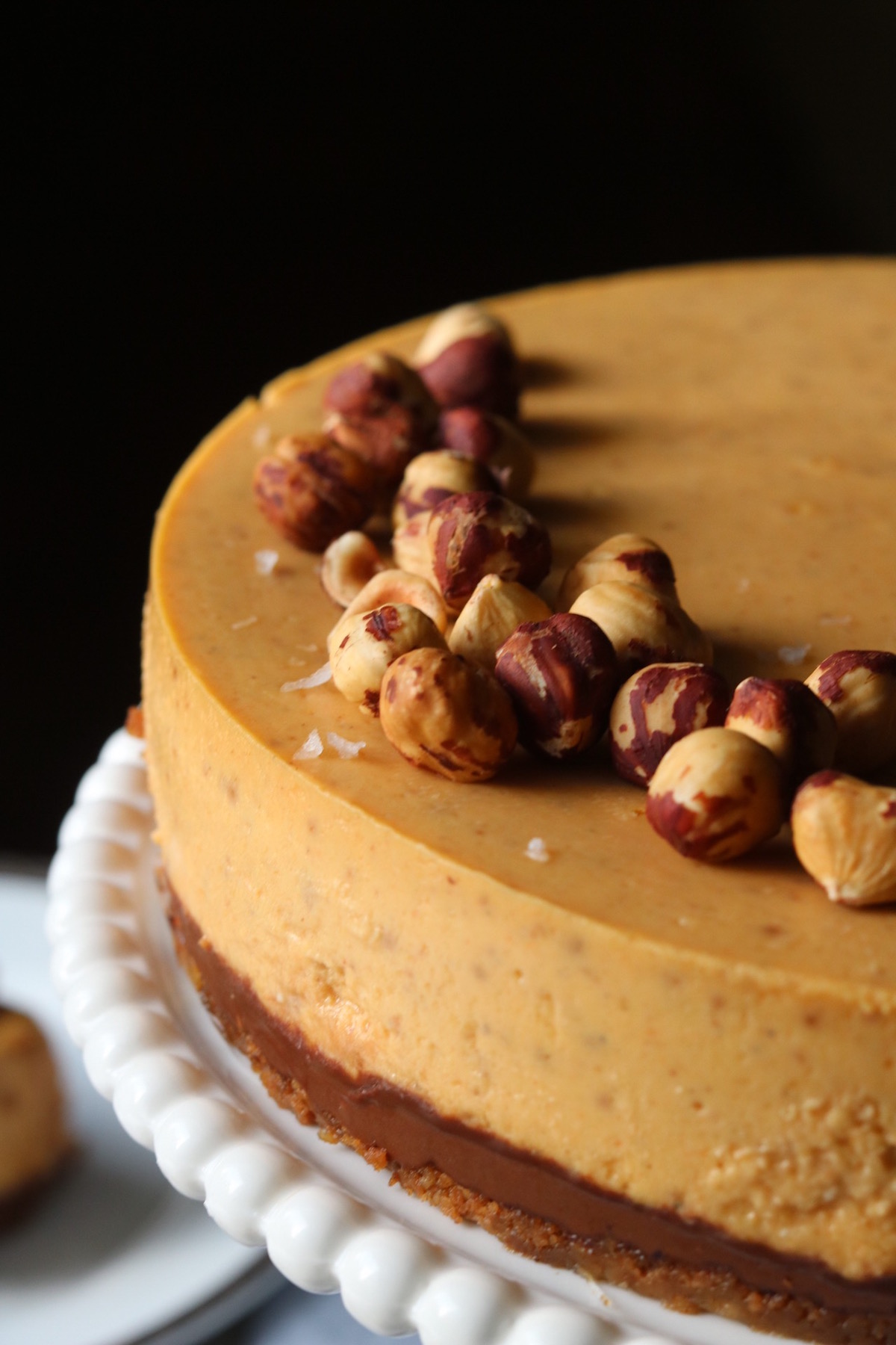 A super close up look at the hazelnuts and sea salt flakes on top of pumpkin cheesecake.