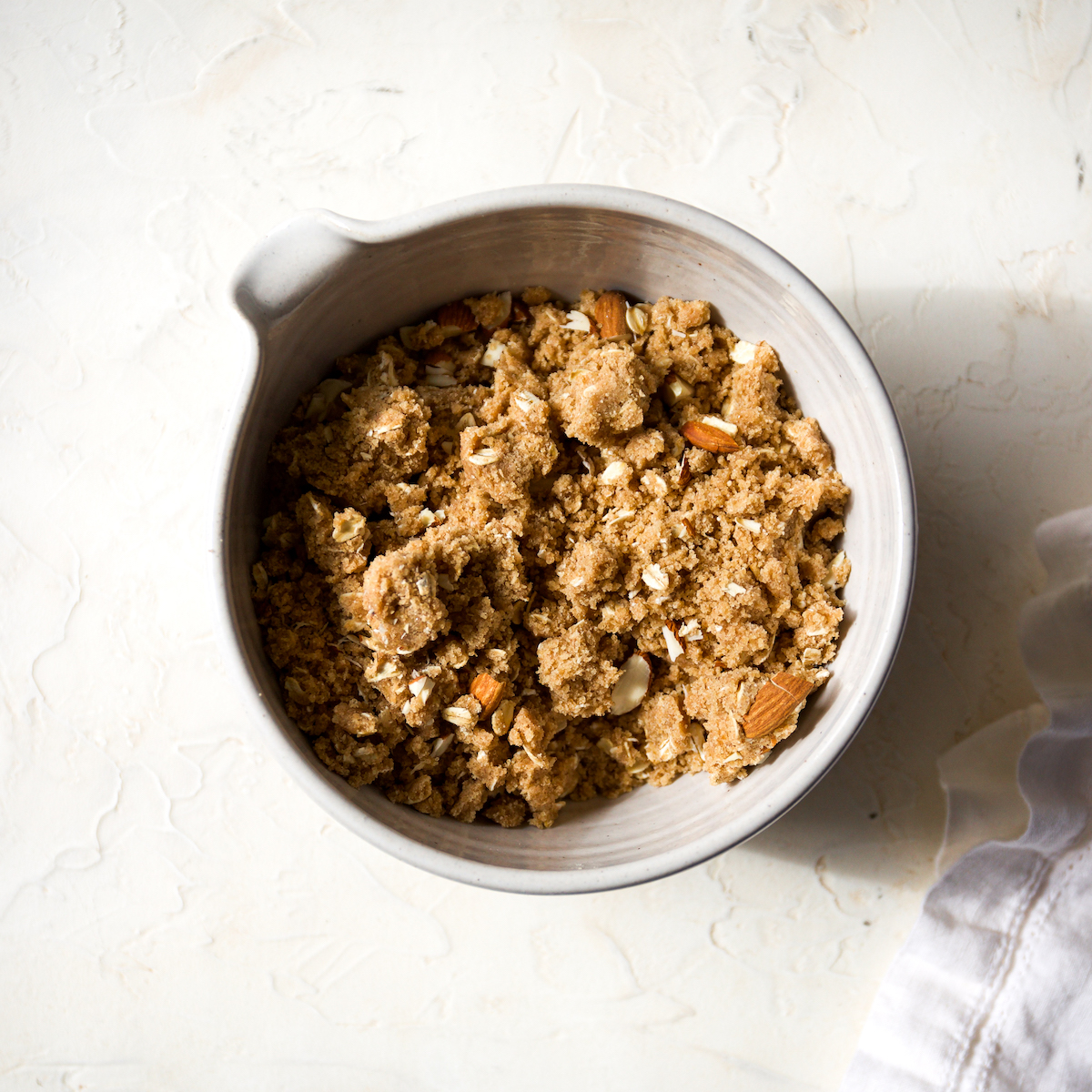 A white bowl filled with oat streusel.