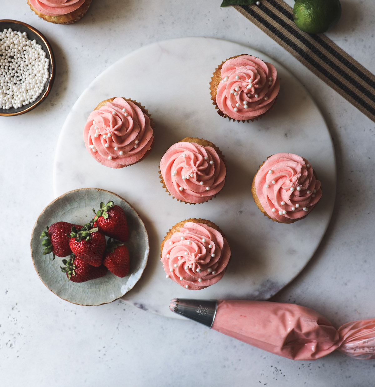 An other head shot of gluten free lime agave cupcakes with some fresh strawberries, a random ribbon and lime. Oh, and some pretty pink  frosting in a pastry bag