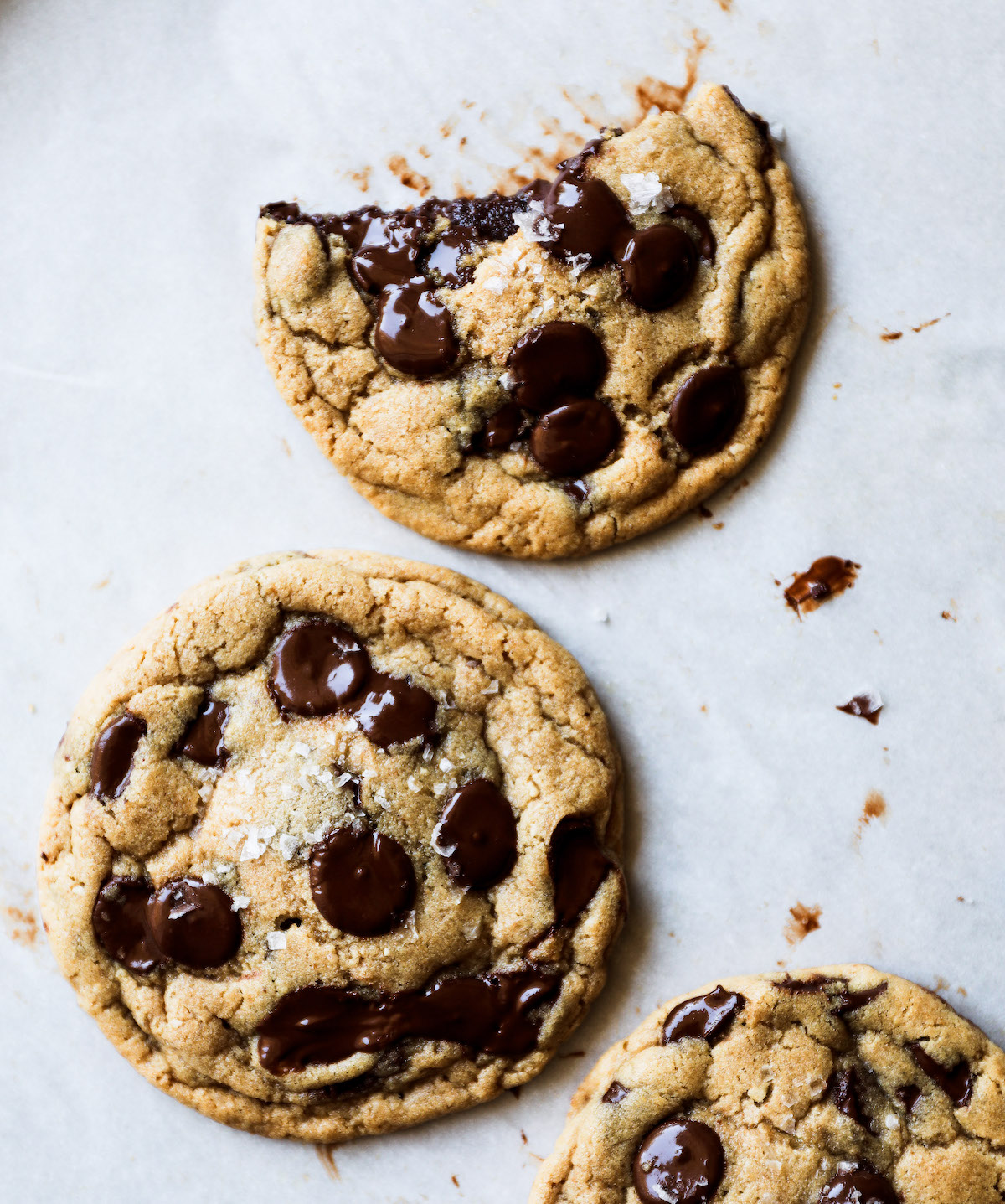 A nutella-stuffed chocolate chip cookie with a big bite out of it on a white surface.