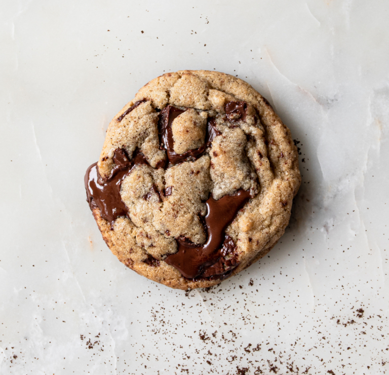 A chocolate chip cookie on a white, marble background