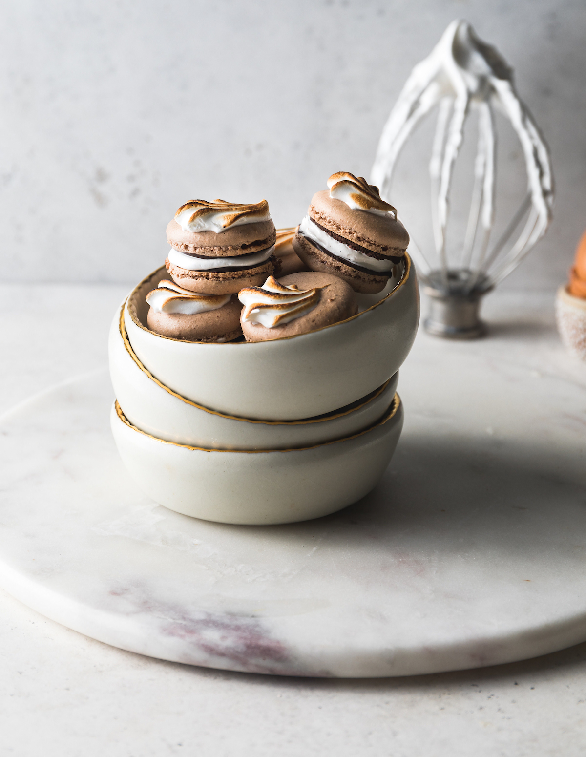 A bowl of chocolate French macarons with marshmallow filling and Mexican hot chocolate glaze