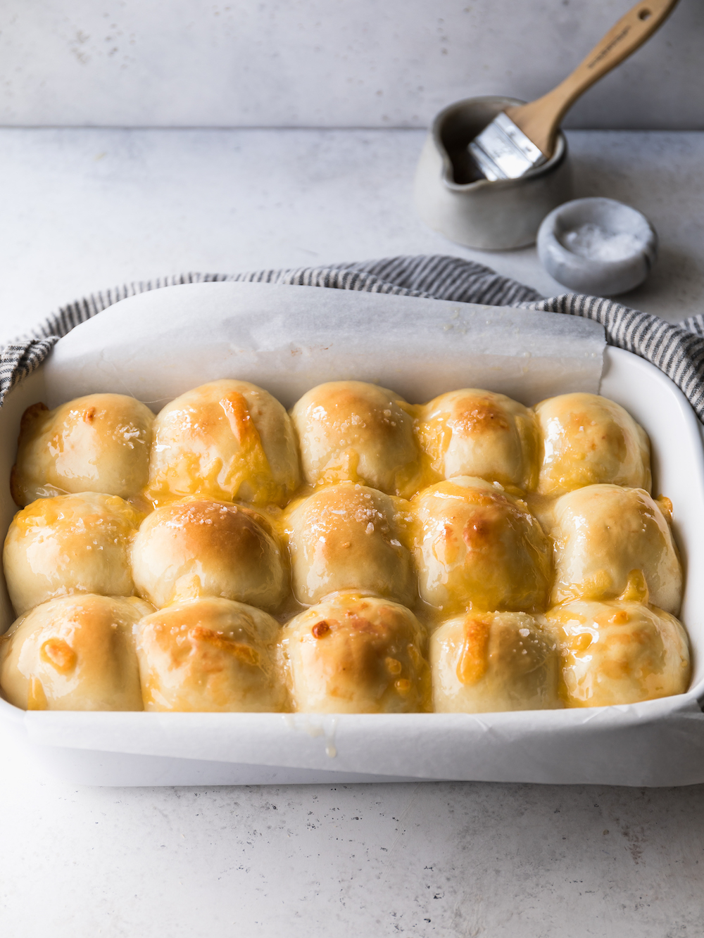 A whole dish of cheesy  dinner rolls.