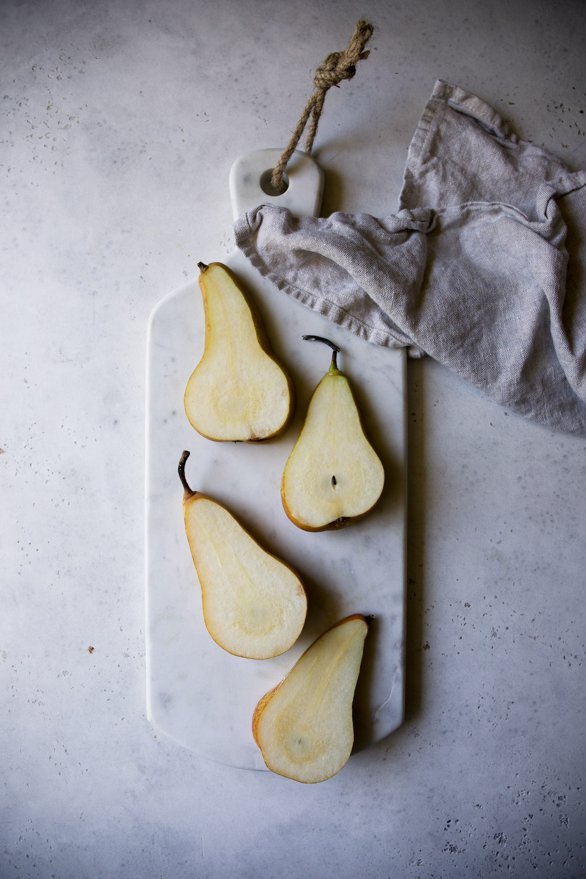 Halved pears on a marble cutting board.