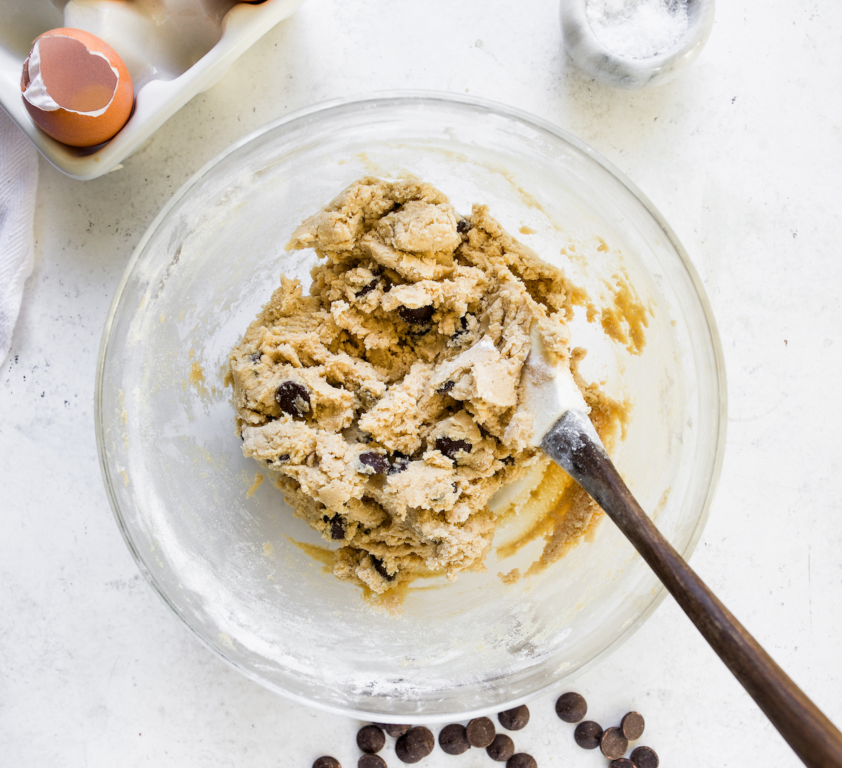 Cookie dough in a glass bowl with a white background.