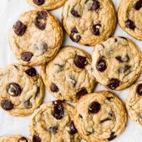 A bunch of big cookies overlapping on a white surface.