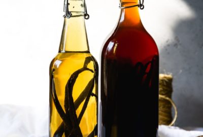 Two bottles of homemade vanilla extract; one bottle is lighter in color and the other is an amber color.