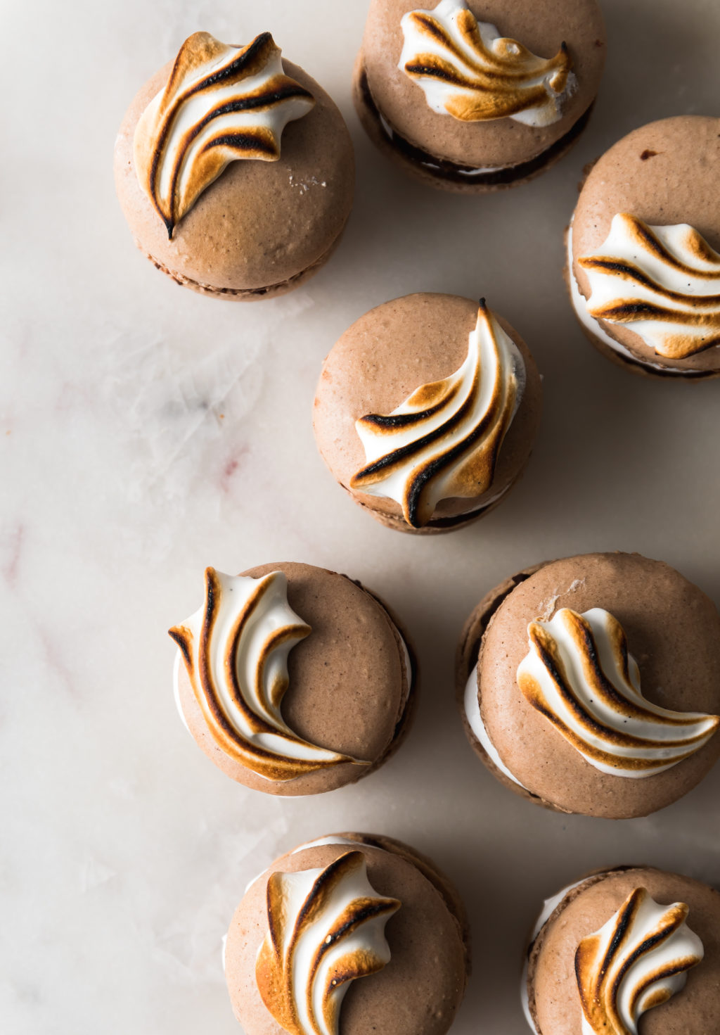 A bunch of chocolate french macarons with marshmallow filling and topped with toasted meringue