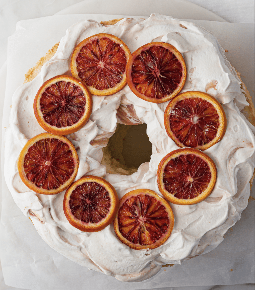Round cake with white icing and slices of citrus on top