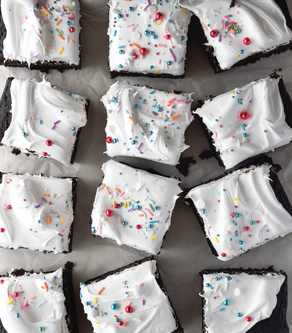 Overhead shot of chocolate cake with white icing and colorful sprinkles on top