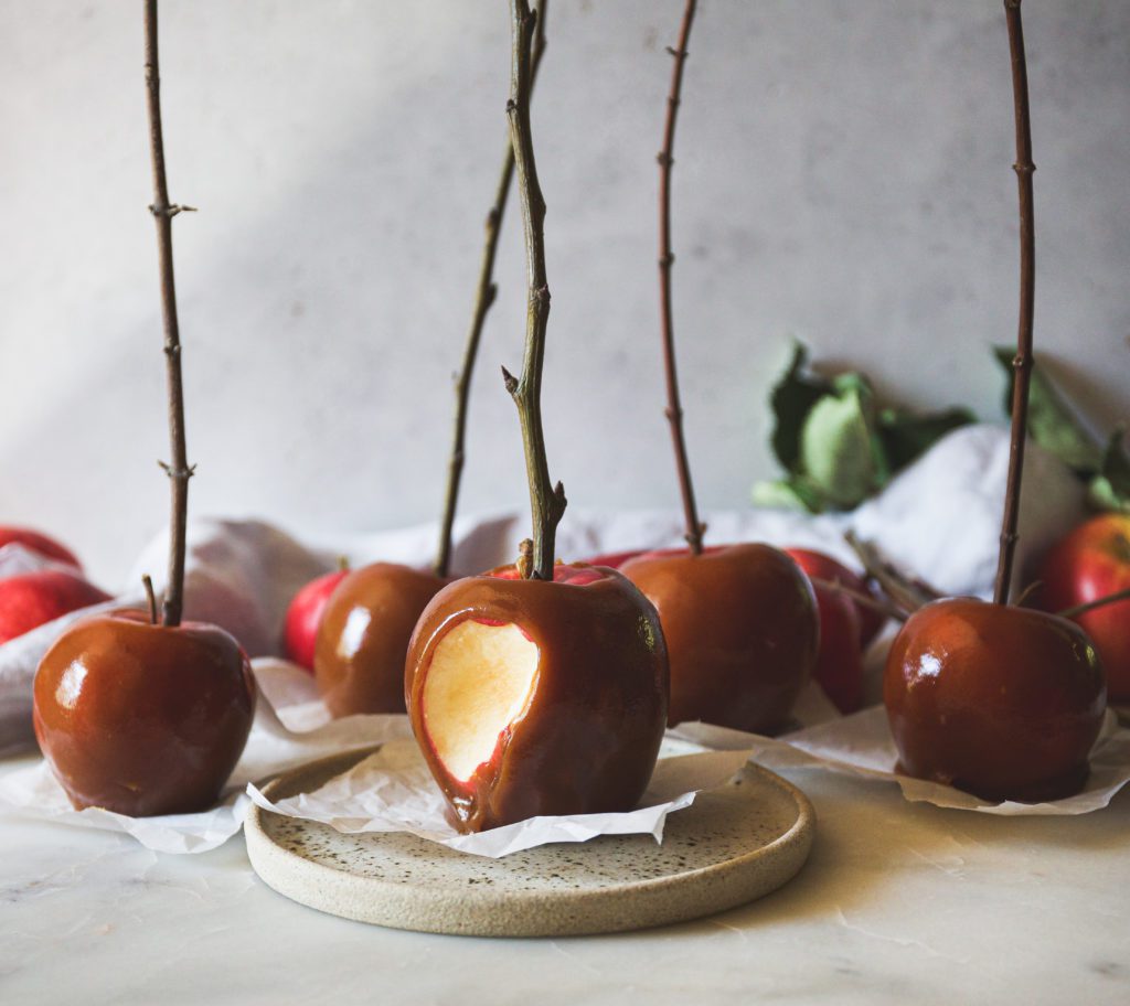 A bunch of caramel apples, one with a bite out of it