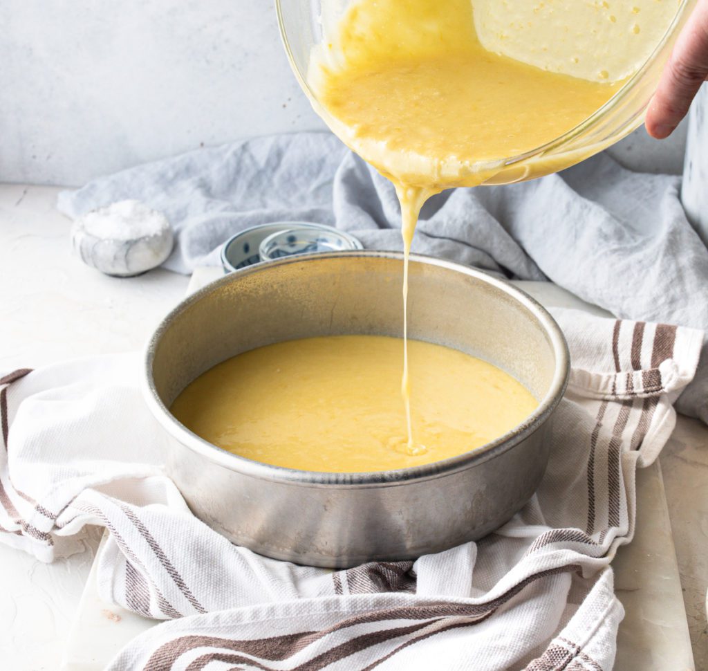 Pouring the lemon olive oil cake batter into a round cake pan