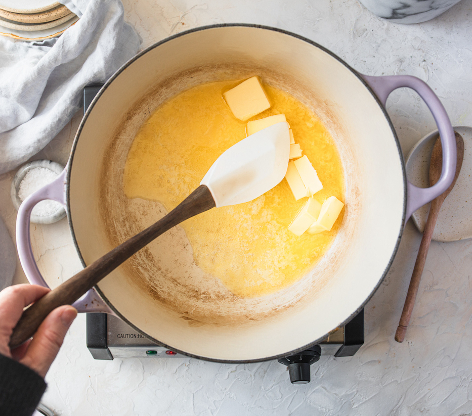 Butter melting in a white-bottomed dutch oven.