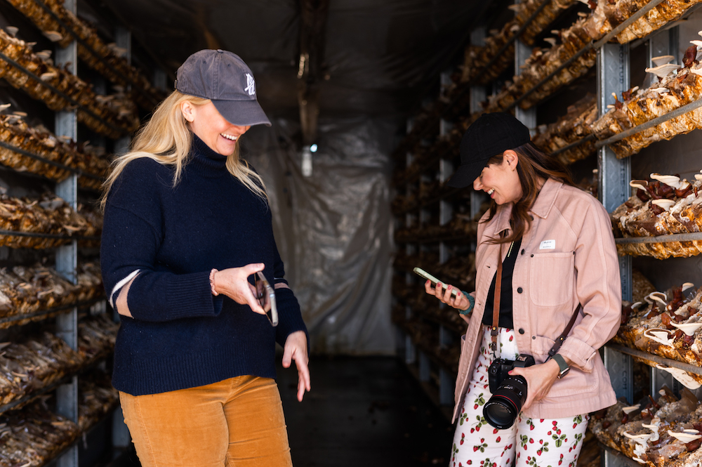 A couple of women that love food laughing at a mushroom farm.  