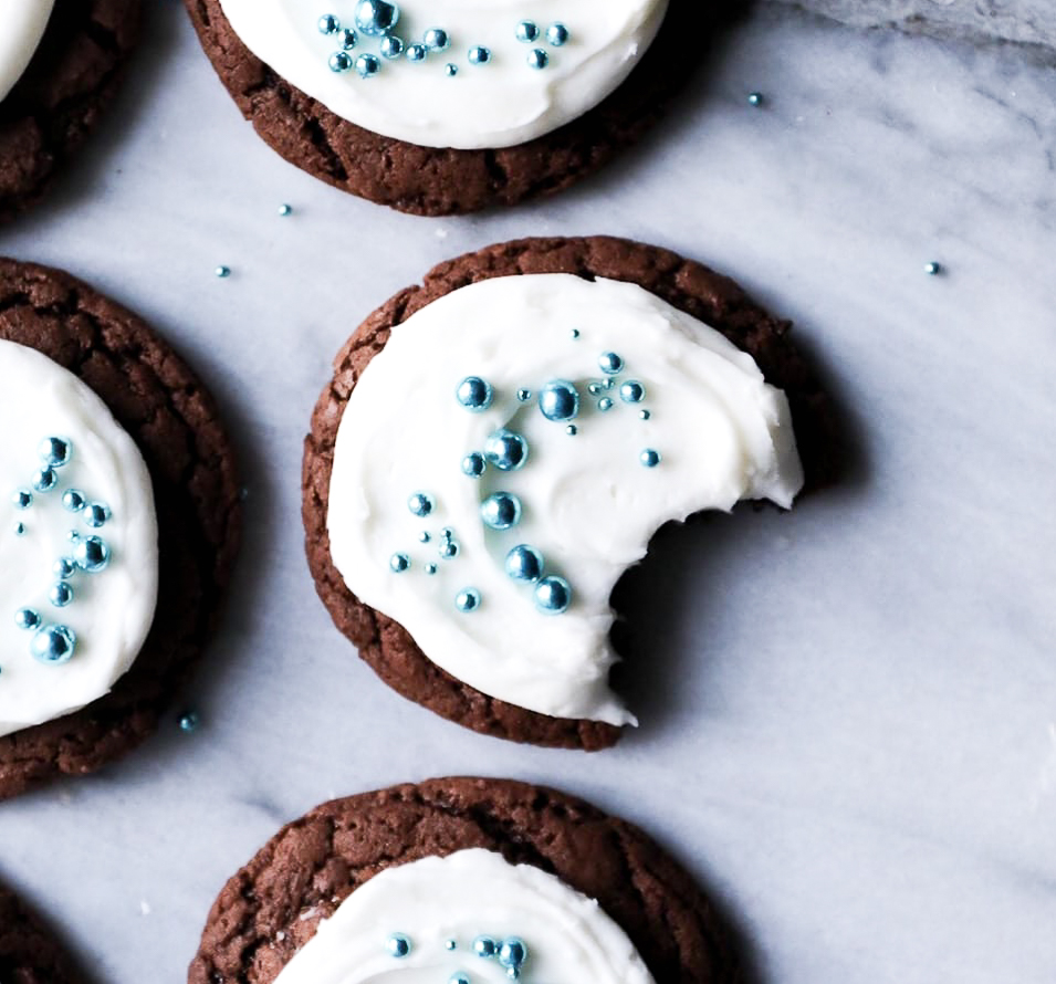 chocolate cookies with a smear of vanilla frosting and sprinkled with pretty blue sprinkles