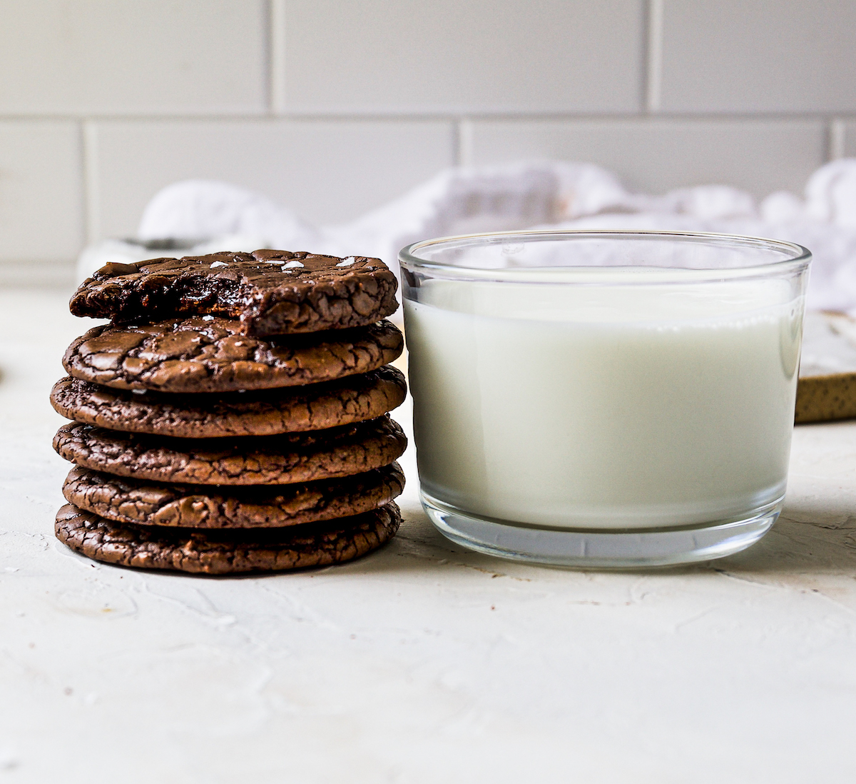 A stack of brownie  cookies and milk