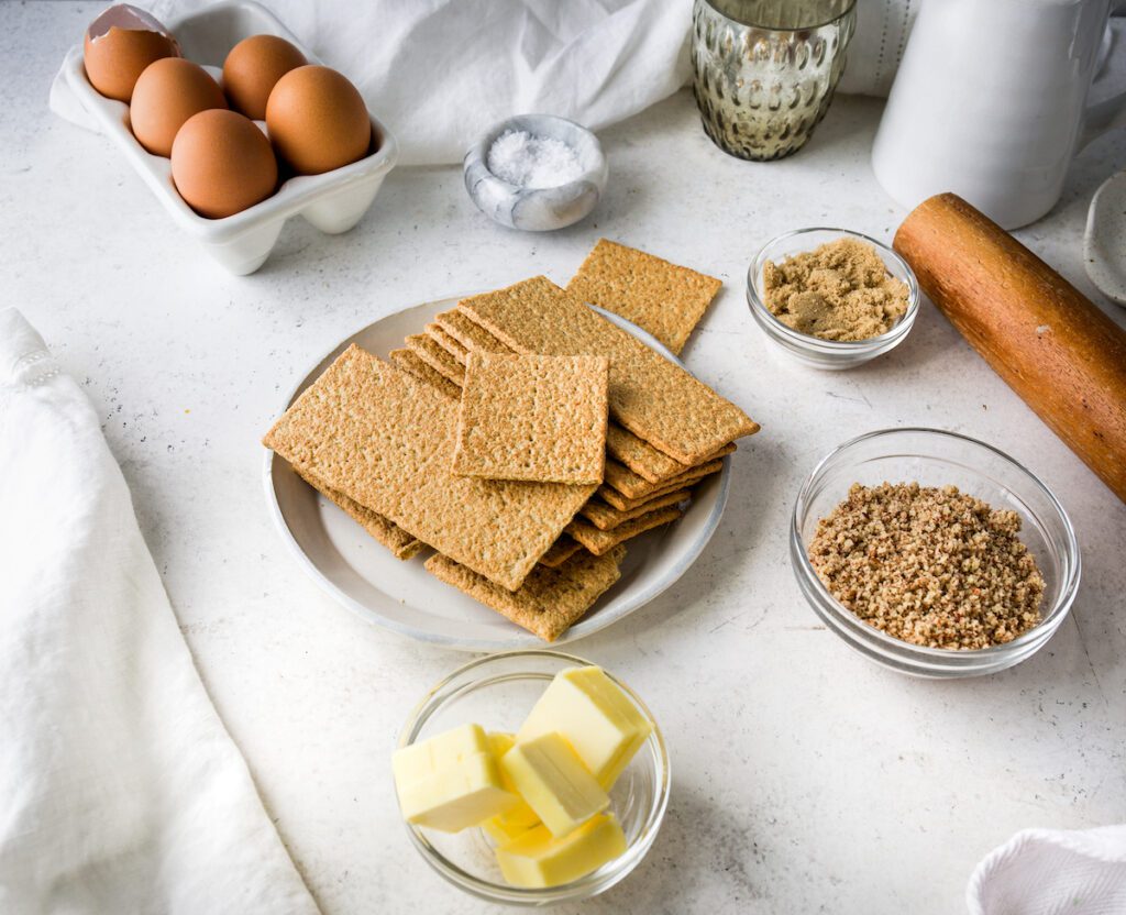 All of the ingredients to make a graham cracker crust on a white background.