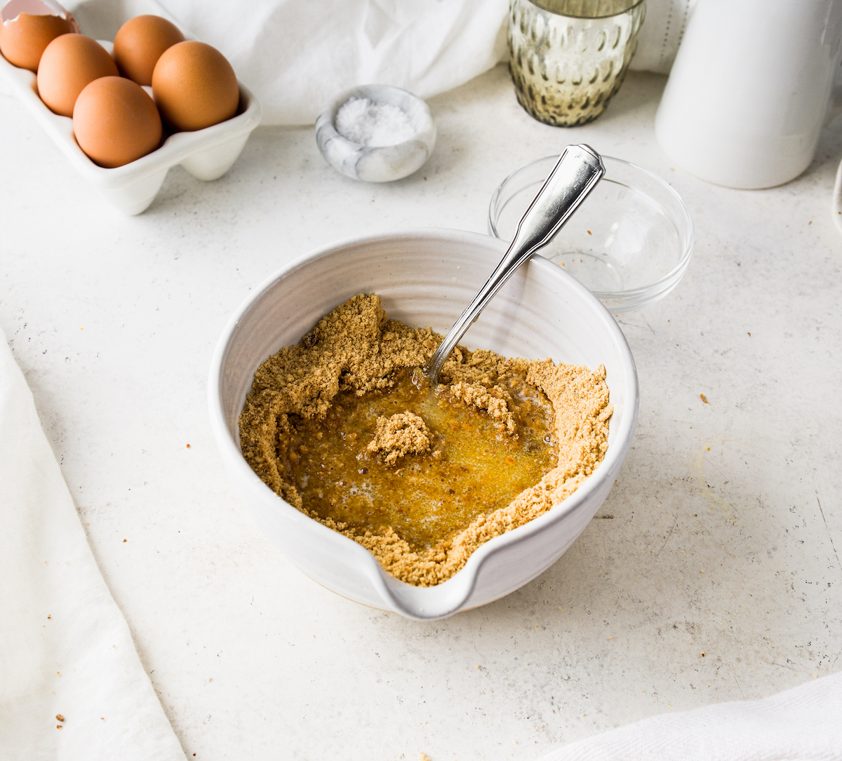 Ground  up graham crackers with melted butter in a bowl.