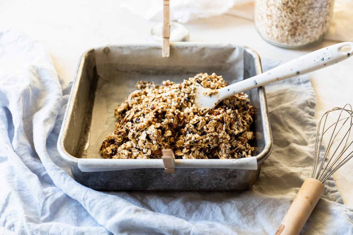 A parchment lined pan filled with granola mixture.