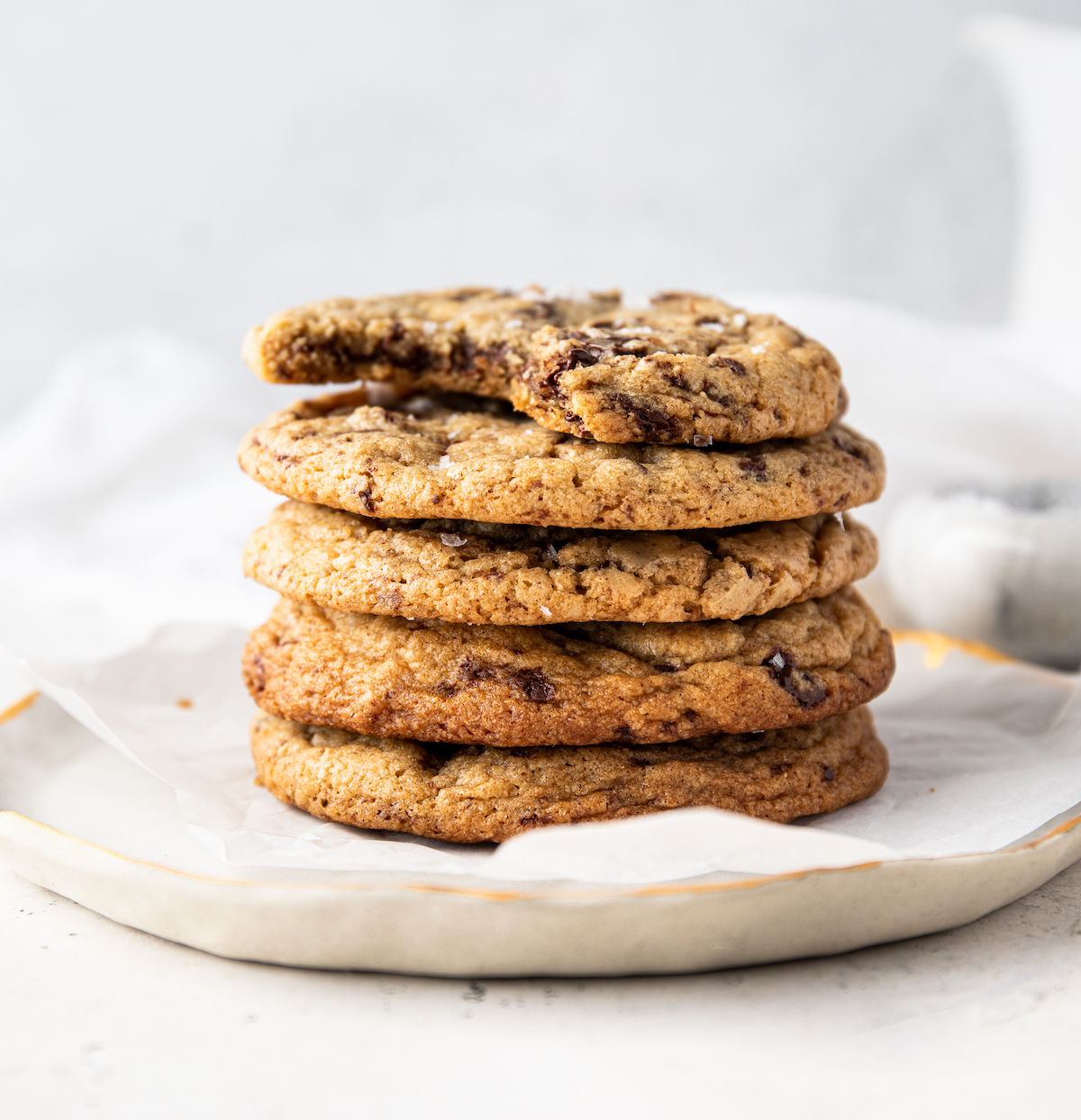 A stack of chocolate chip cookies on a plate with a white background.