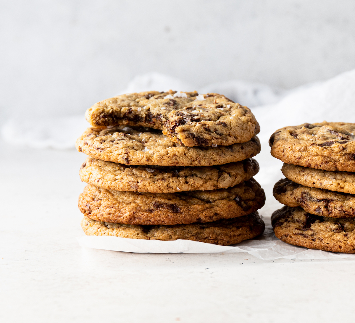 Two stacks of brown butter chocolate chip cookies with a white background.