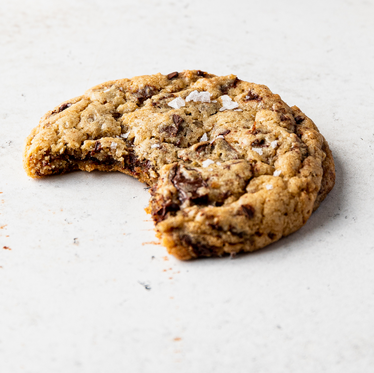 A close up shot of a chocolate chip cookie with a bite out of it.