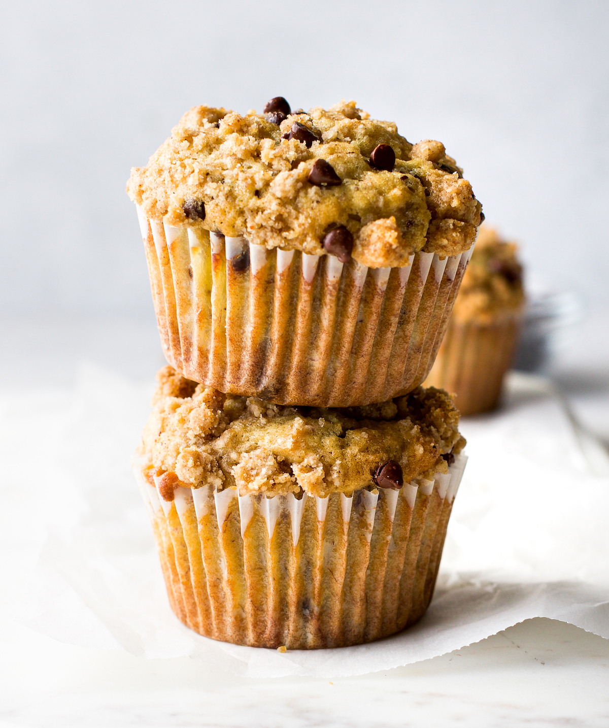 Two banana chocolate chip muffins stacked on top of each other.