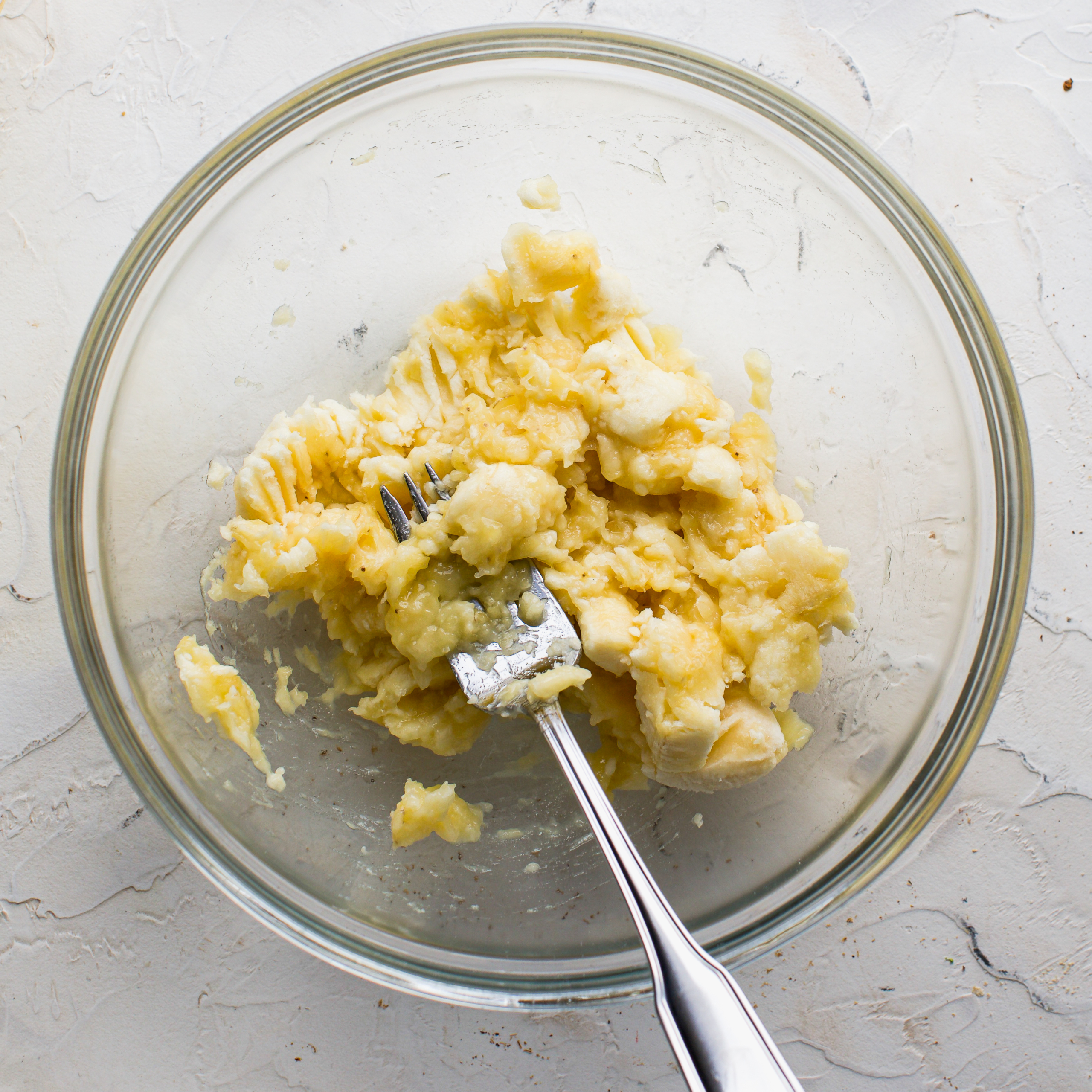 A glass bowl with mashed bananas.