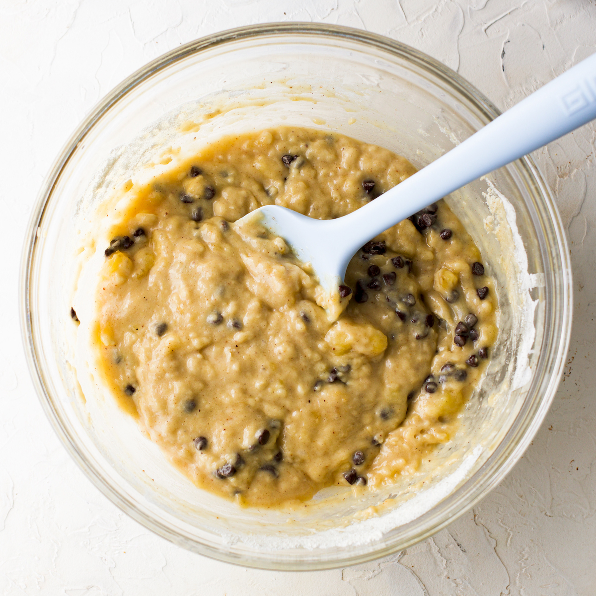 A close  up of a glass bowl with banana chocolate chip muffin batter.