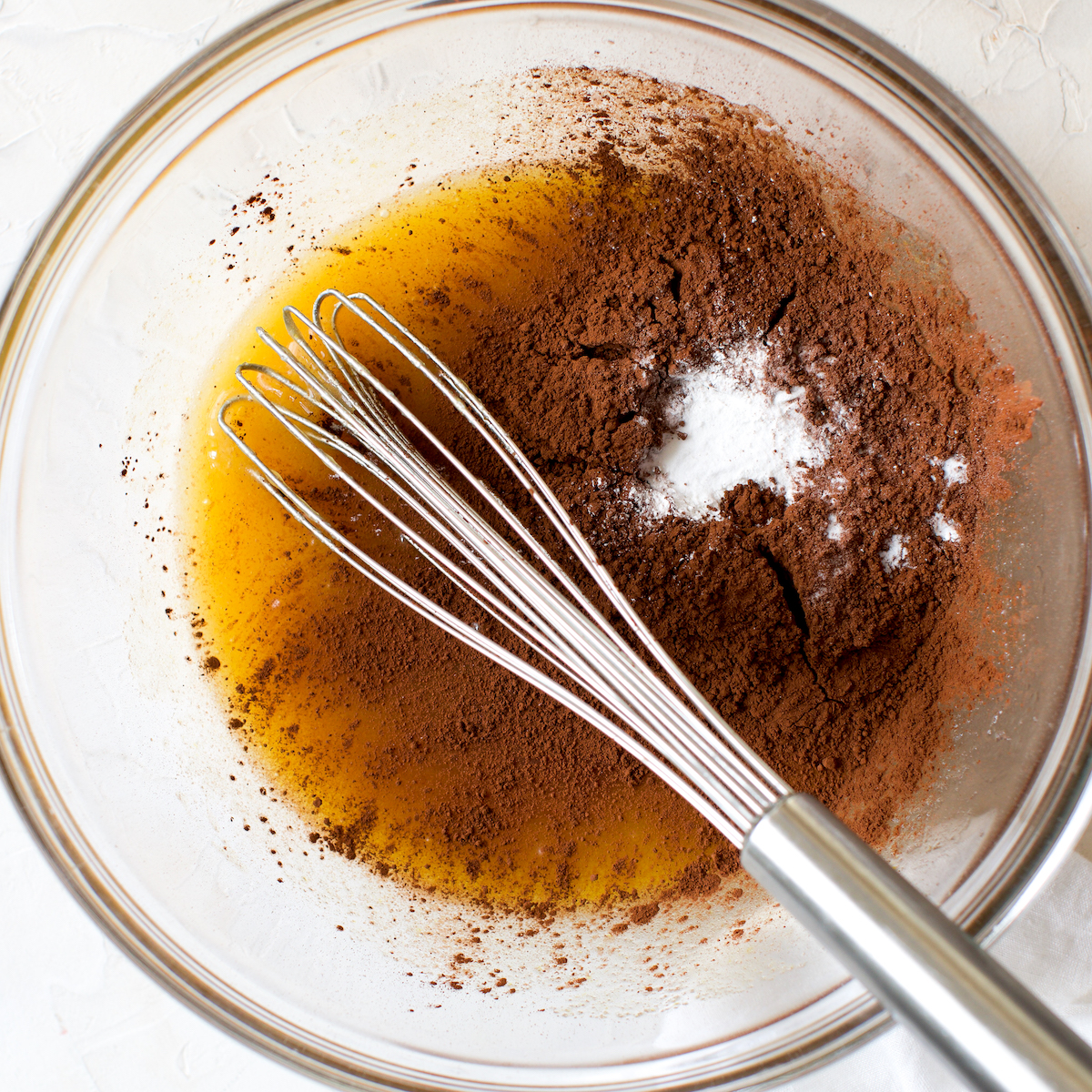 Cocoa powder and leavening in a bowl of wet cake ingredients. 