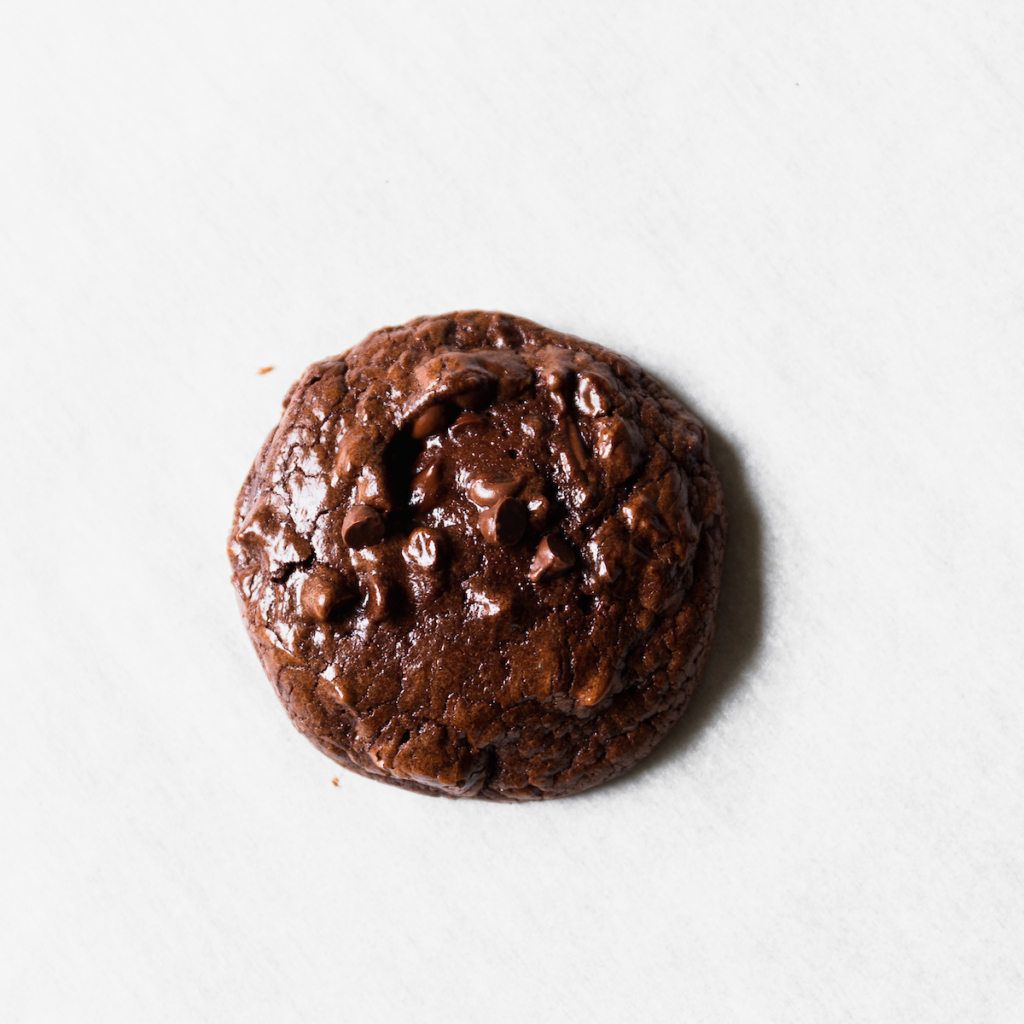A close up of a chocolate brownie cookie on a white surface.