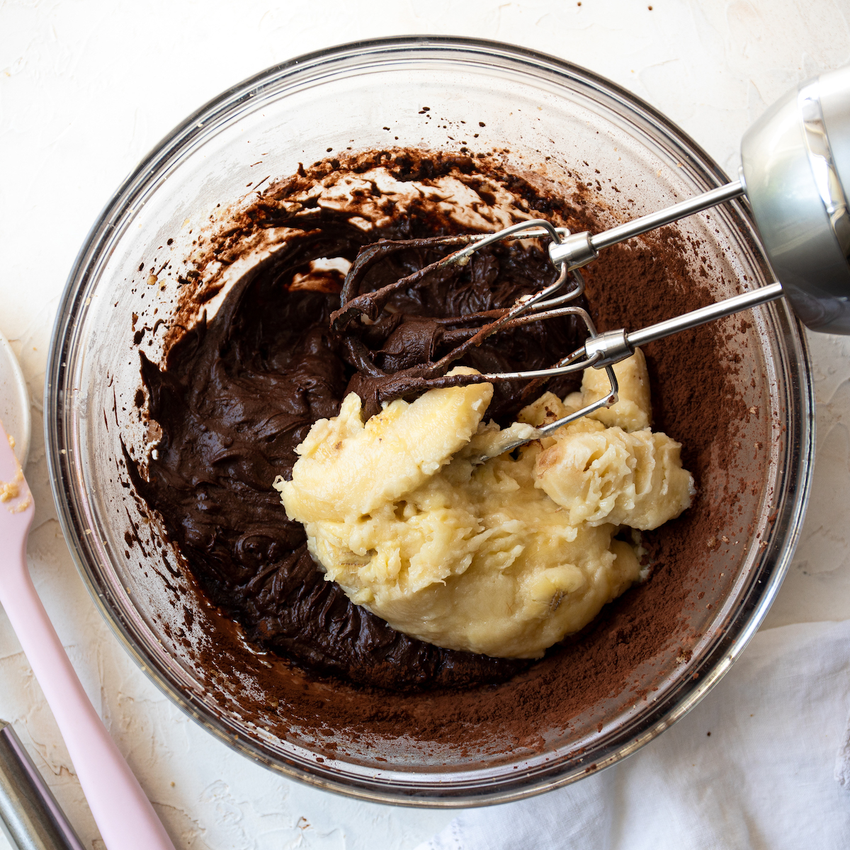 A bowl of chocolate cake batter with mashed bananas on top.