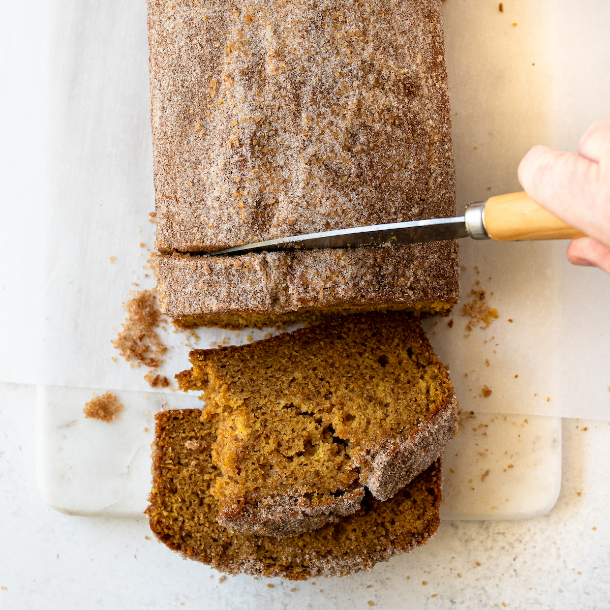 A knife cutting slices of pumpkin bread.