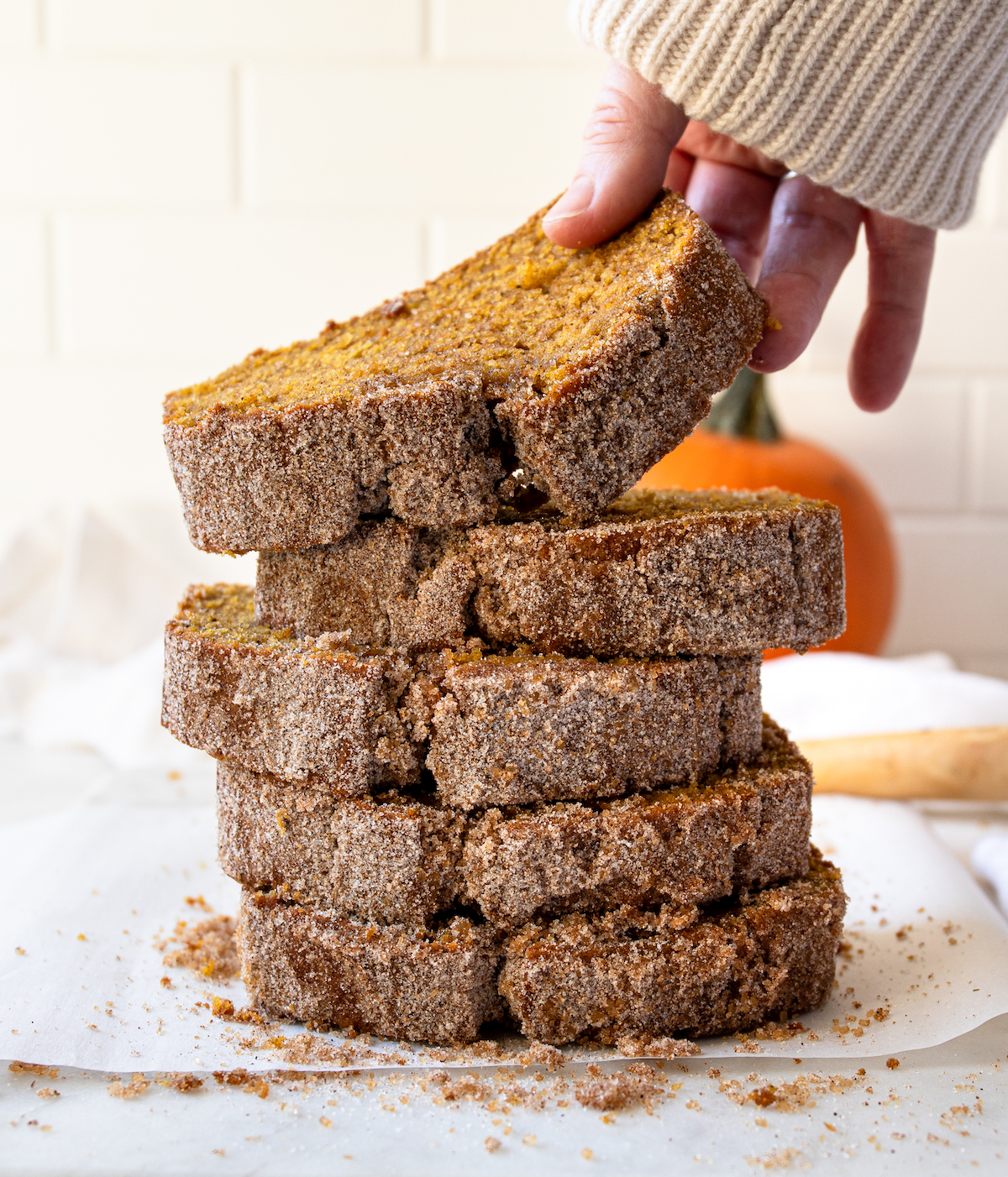 Stack of pumpkin bread slices with a hand grabbing one.