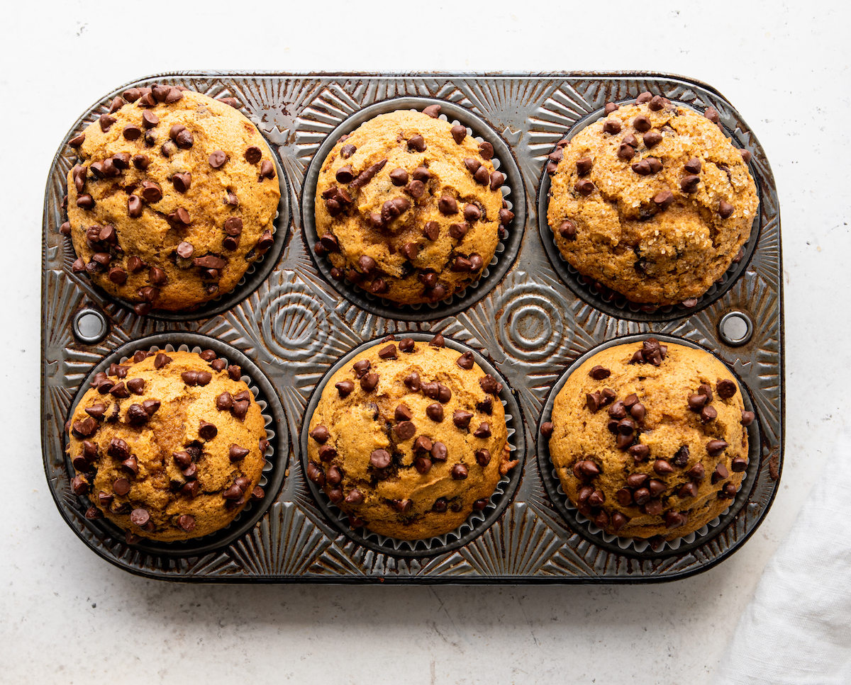 A muffin pan of pumpkin muffins with chocolate c hips