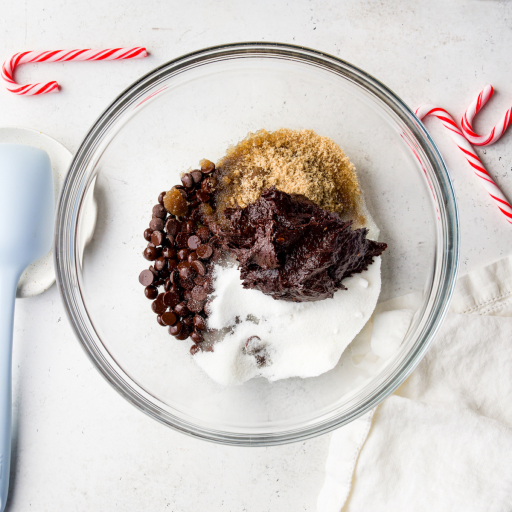 A glass bowl that has chocolate chips, brown sugar, granulated sugar and the flaxseed prune mixture.