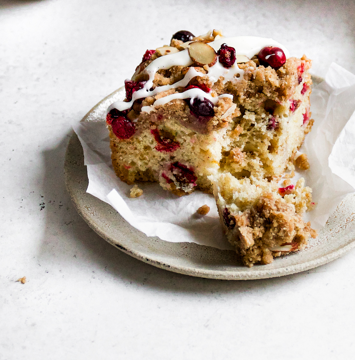 A close up of a piece of cranberry coffee cake with streusel and almonds.