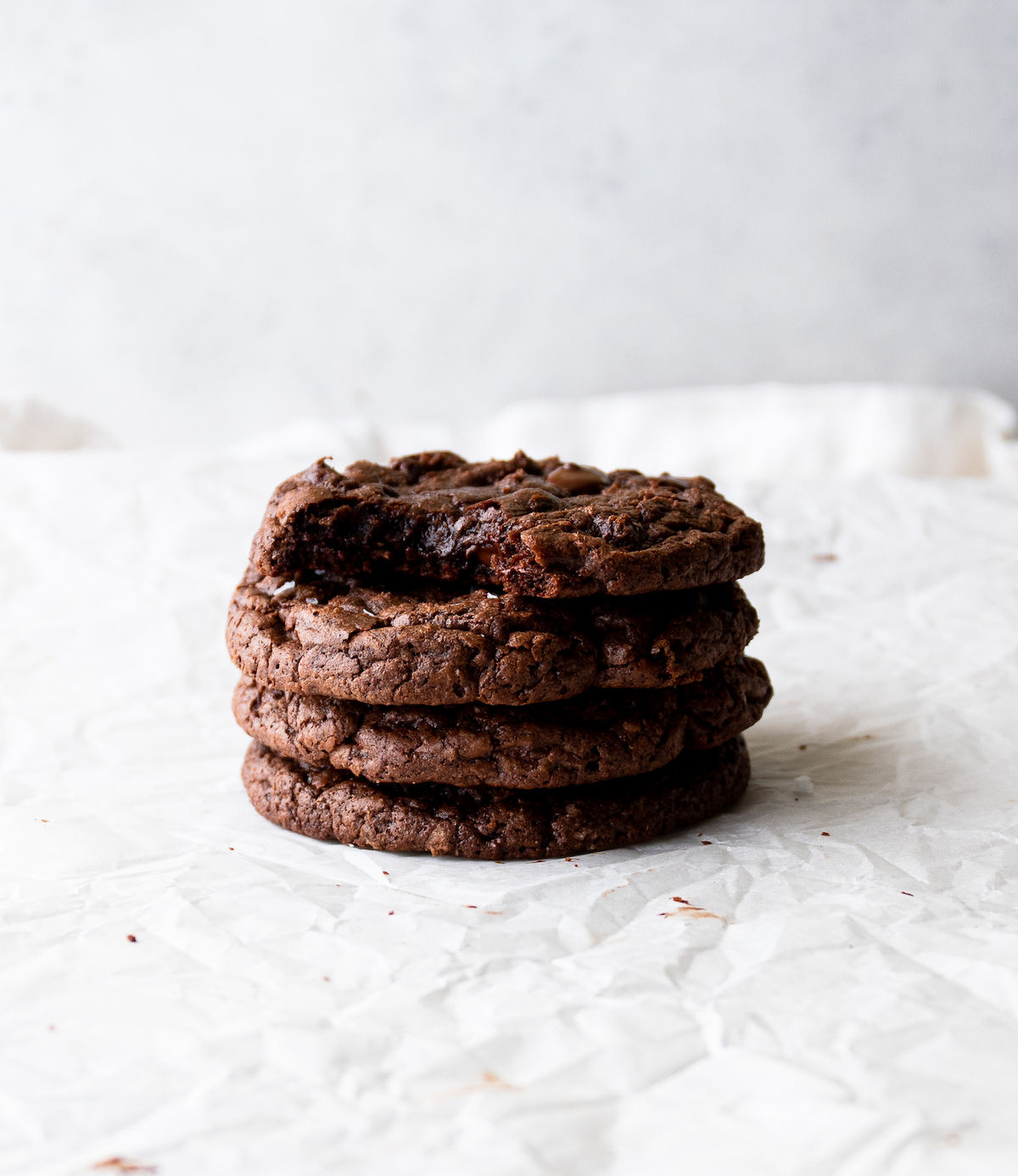 A stack of chocolate cookies with the top one missing a bite.