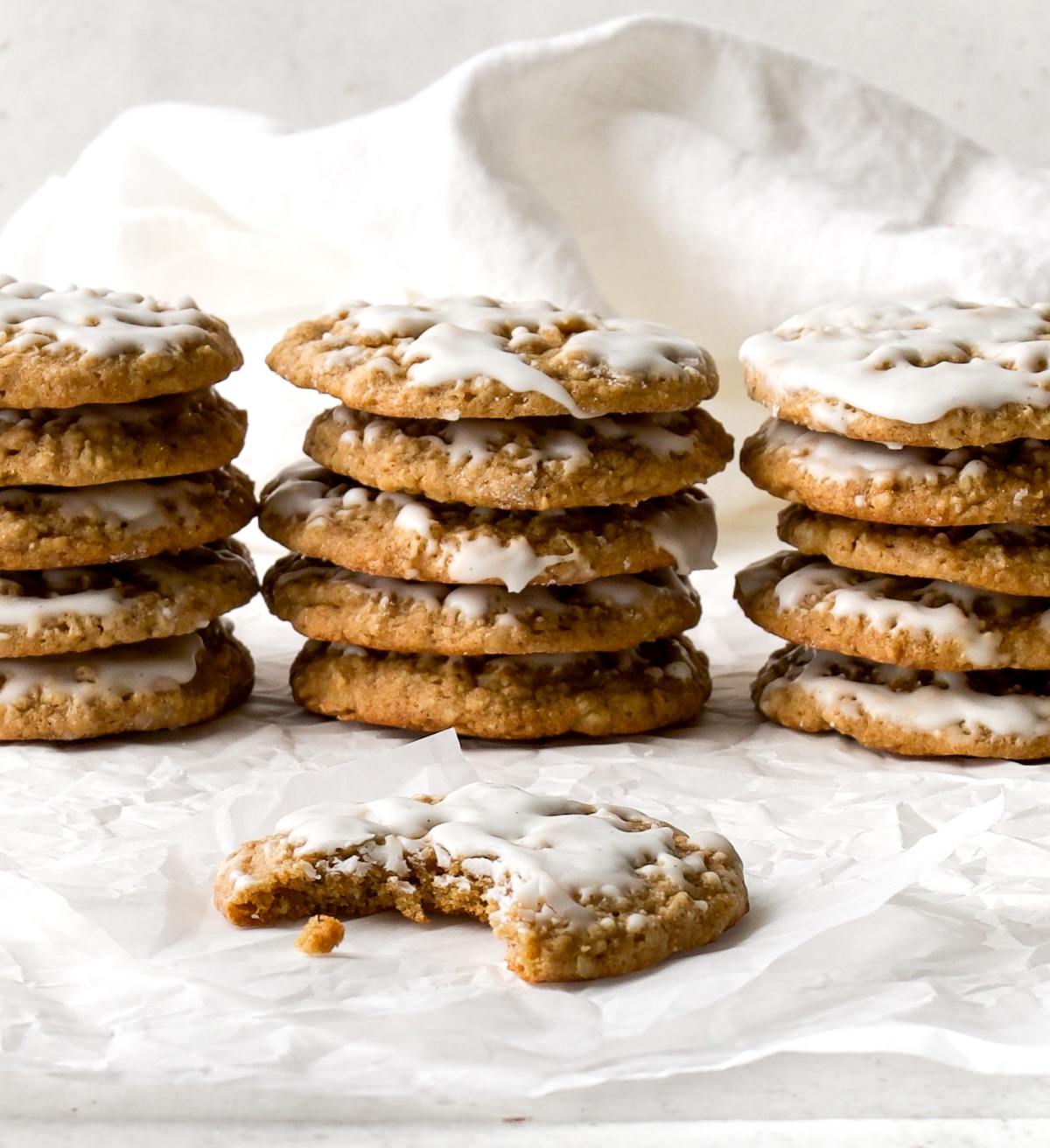 Three stacks of cookies with one cookie in front with a bite out of it.